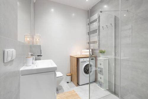 a bathroom with a washing machine and a sink at Elite Apartments Garden Gates Premium in Gdańsk