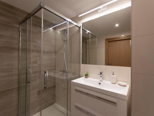 uma casa de banho com um lavatório e uma cabina de duche em vidro. em VacationClub – Seaside Park Apartament 316 em Colberga