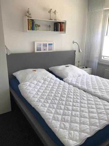 a bedroom with a bed with a white comforter at Ferienwohnung Wittje in Butjadingen