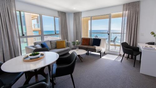 a living room filled with furniture and a large window at Oaks Glenelg Plaza Pier Suites in Adelaide