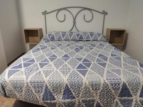 uma cama com uma colcha azul e branca em Dúplex con terraza en El Bosque em El Bosque