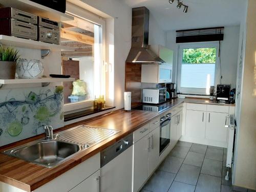 uma cozinha com armários brancos, um lavatório e uma janela em STHS79005-FeWo-Meerruschen em Meeschendorf