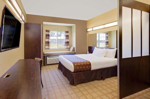 a hotel room with a large bed and a television at Microtel Inn & Suites by Wyndham Prairie du Chien in Prairie du Chien