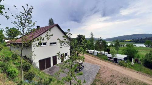 una casa blanca en una colina con un camino de tierra en Camping Haus Seeblick, en Gütenland