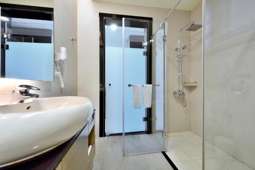 y baño con lavabo y ducha acristalada. en Shinkansen Grand Hotel en Taichung