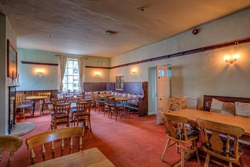 un restaurante con mesas de madera y sillas en una habitación en Kings Head Hotel, en Kirkbymoorside