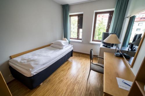 a small room with a bed and a desk and window at Summer Hotel Tott in Savonlinna