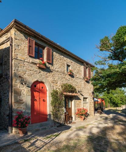 a stone building with a red door and a tree at Monastero San Silvestro in Cortona
