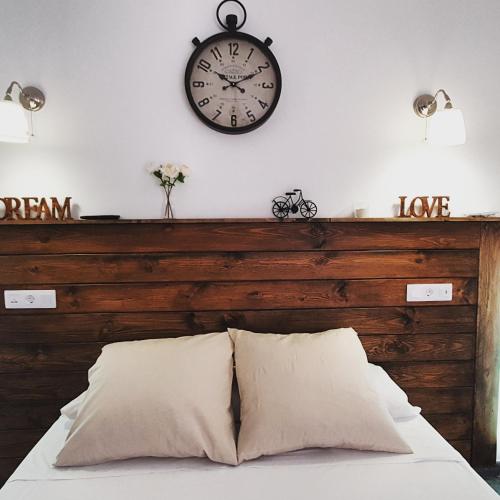a clock on a wall above a bed with pillows at El Nogal Home in Málaga
