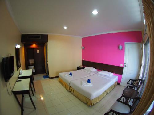 een hotelkamer met een bed en een roze muur bij Jed Pee Nong Hotel โรงแรมเจ็ดพี่น้อง in Hua Hin
