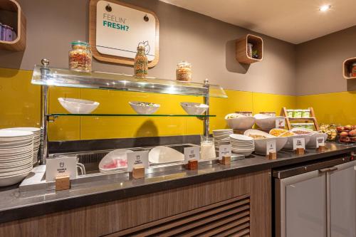 a kitchen with a counter with plates and food at Holiday Inn Express Edinburgh Airport by IHG in Ingliston