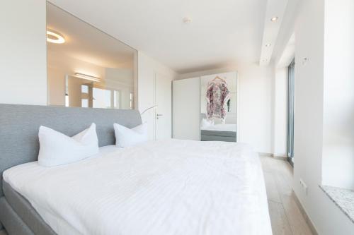 ein weißes Schlafzimmer mit einem großen Bett mit weißen Kissen in der Unterkunft Haus Verando - Apartment Meeresrauschen II in Binz