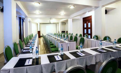 a row of tables in a room with green chairs at Maru Maru Hotel in Zanzibar City