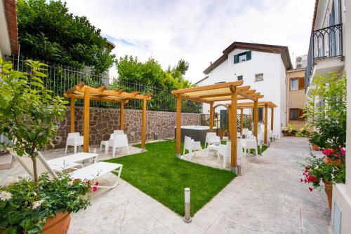 a garden with a wooden pergola and white chairs at Ravello House in Ravello