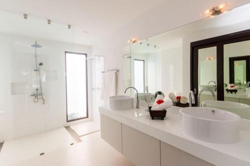 a white bathroom with two sinks and two mirrors at Malee Beach A4 in Ko Lanta