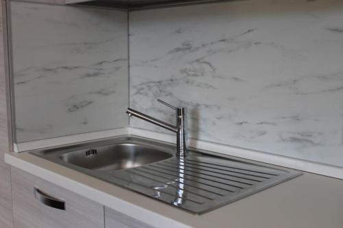a stainless steel sink in a white kitchen at In centro Ca' Leandro Vista lago in Lierna