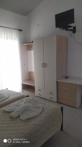 a bedroom with a bed and a dresser and a television at Monika Hotel Sidari in Sidari