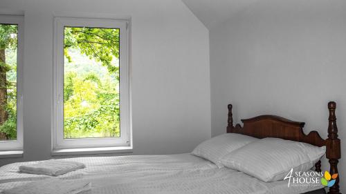 a white bedroom with a bed and a window at 4 Seasons - House in Sub Cetate