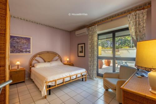 una camera con un letto e una sedia e una finestra di House&Villas - Eden Charming House ad Avola