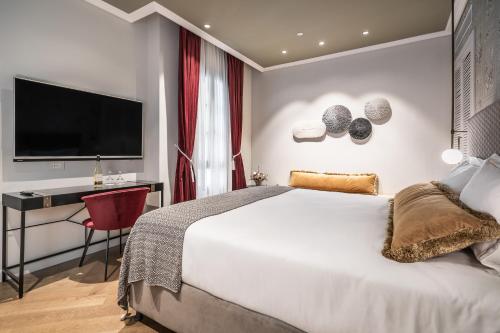 a bedroom with a bed and a desk and a television at Zamarin Hotel & Spa in Zikhron Ya‘aqov