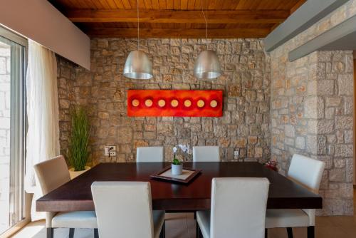 a dining room with a wooden table and white chairs at Villa CostaMare - enjoy lazy days on the private Pool-Jacuzzi in Pefki Rhodes
