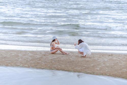 two women sitting on the sand on the beach at Veranda Residence Pattaya Nice Monthly rate available now in Na Jomtien
