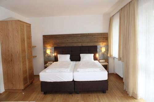 a bedroom with a large bed with white sheets at Hotel Rauscher - Das Naturteichparadies in Bad Hofgastein