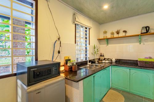 a kitchen with blue cabinets and a microwave at Tan Thanh Garden Homestay in Hoi An