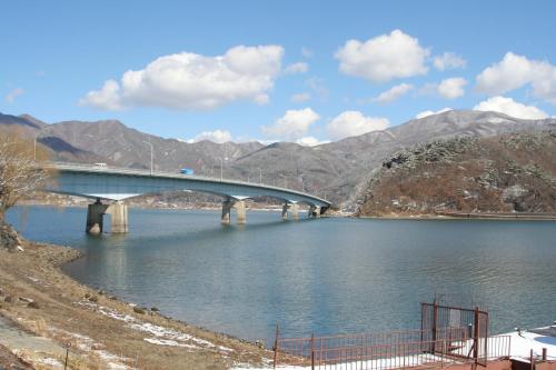 a bridge over a lake with mountains in the background at Shiki-no-Yado Fujisan in Fujikawaguchiko