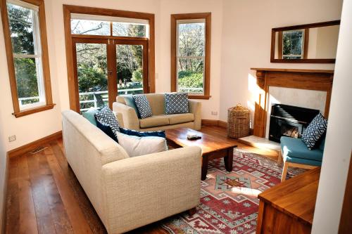 a living room with two chairs and a fireplace at Elegant Villa Nestled In The Trees in Nelson