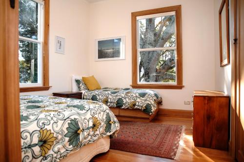1 dormitorio con 2 camas y 2 ventanas en Elegant Villa Nestled In The Trees en Nelson