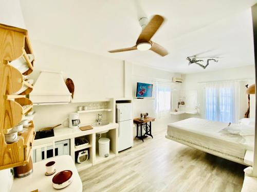 a white bedroom with a bed and a ceiling fan at Deluxe Studios & Suites Ageri-Milos in Adamantas