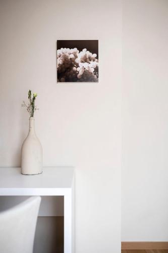 a white vase on a white table with a picture at Schloss Plars wine & suites in Lagundo