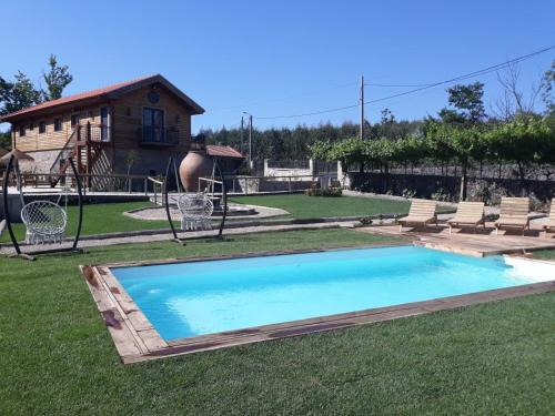 uma piscina num quintal com cadeiras e um parque infantil em Quinta Ze do Coval em Arouca