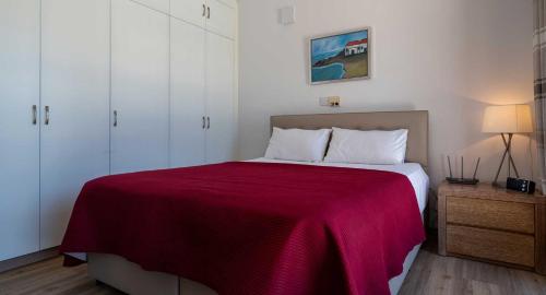 a bedroom with a large bed with a red blanket at 3 bedroom Villa Melandra with private pool and sea views, Aphrodite Hills Resort in Kouklia