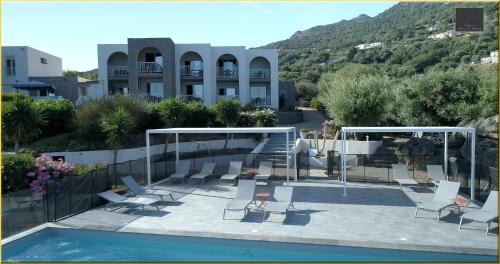 une piscine avec des chaises et une table ainsi qu'un bâtiment dans l'établissement Résidence Roc e Mare, à LʼÎle-Rousse