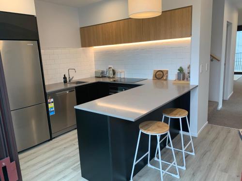 a kitchen with a counter and two stools at One central apartments city centre in Christchurch