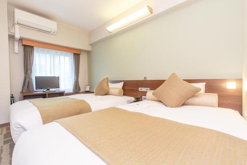 a hotel room with two beds and a television at Rembrandt Style Yokohama Kannai in Yokohama