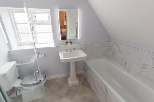 a white bathroom with a sink and a tub and a toilet at The Old Vicarage Hotel & Restaurant in Bridgwater