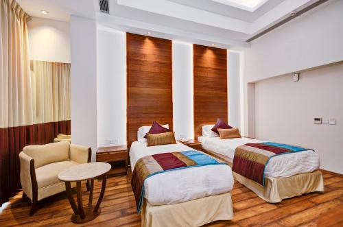 a hotel room with two beds and a chair at La Sagrita in New Delhi