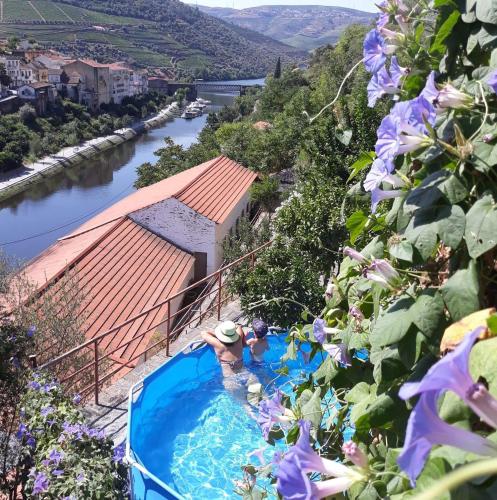 a person in a swimming pool next to a river at Casa da Encosta Douro Valley in Pinhão
