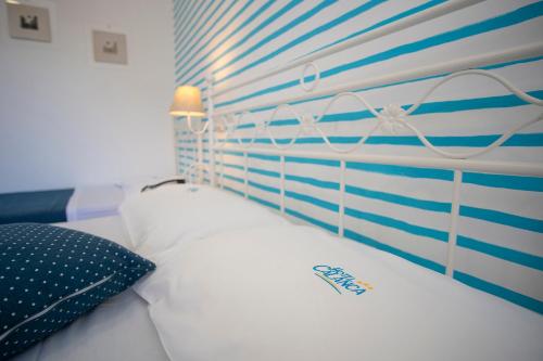 a white bed with a blue and white striped wall at Hotel Calanca in Marina di Camerota