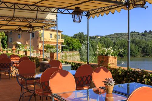 a restaurant with tables and chairs and a view of a river at Villa La Massa in Bagno a Ripoli