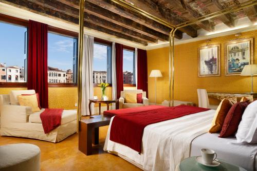 a hotel room with a bed and chairs and windows at Hotel Palazzo Giovanelli e Gran Canal in Venice