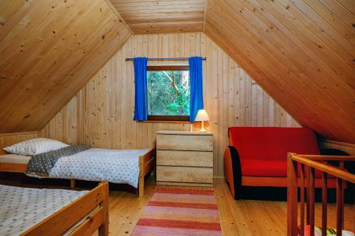 ヤストシェンビャ・グラにあるDomek obok Willi w Rozewiuの屋根裏のベッドルーム(ベッド1台、赤い椅子付)