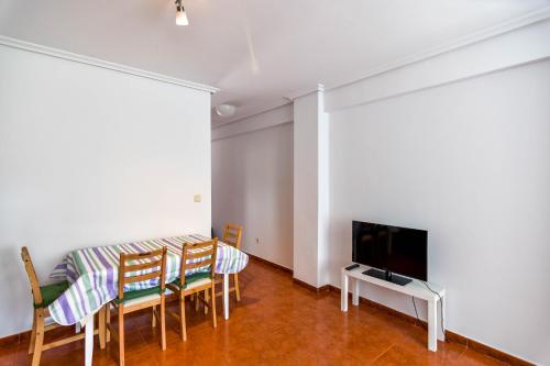 een woonkamer met een tafel en stoelen en een televisie bij ¡Nuevo! Apartamento para 4 en playa de la Concha en Suances in Suances