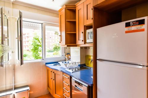 een keuken met een witte koelkast en houten kasten bij ¡Nuevo! Apartamento para 4 en playa de la Concha en Suances in Suances