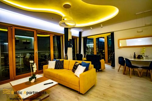 a living room with a yellow couch and a table at Baltic Apartments - Platan Tower in Świnoujście