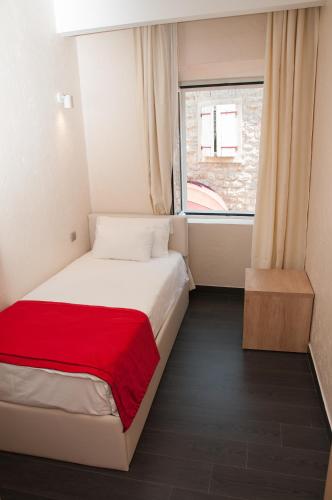 a small bedroom with a bed with a red blanket at Hotel Astoria in Budva
