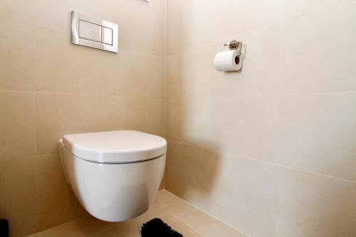 een badkamer met een toilet en een rol toiletpapier bij Modern Balcony Apartment with Pool close to Lake in "Donaustadt" in Wenen